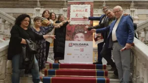 Los promotores del acto de presentación de la XSolidaria posan junto con un rollout de la campaña